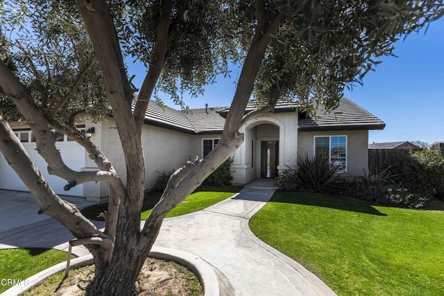 view of front facade featuring a front lawn, a tiled roof, an attached garage, and stucco siding