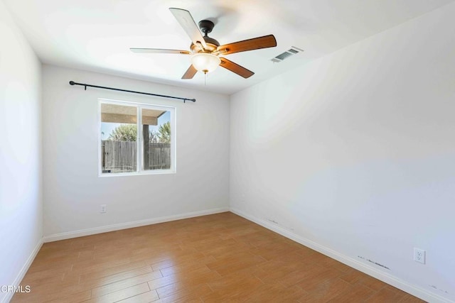 spare room featuring ceiling fan, light wood-style floors, visible vents, and baseboards