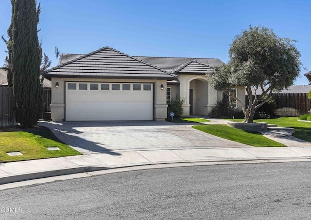 view of front facade featuring fence, a tiled roof, concrete driveway, stucco siding, and an attached garage