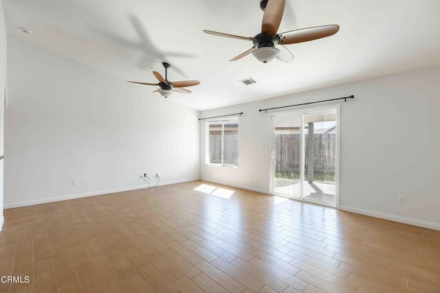 empty room featuring vaulted ceiling, visible vents, baseboards, and wood finished floors