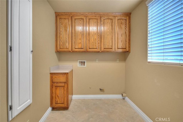 clothes washing area with hookup for a washing machine, cabinet space, and baseboards