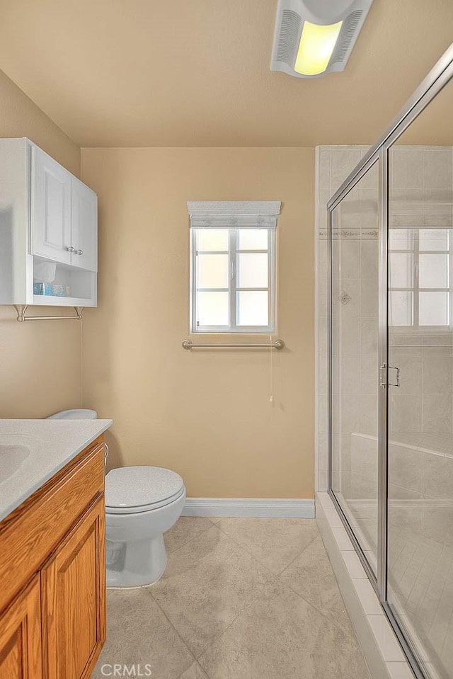 bathroom with baseboards, toilet, vanity, and a shower stall