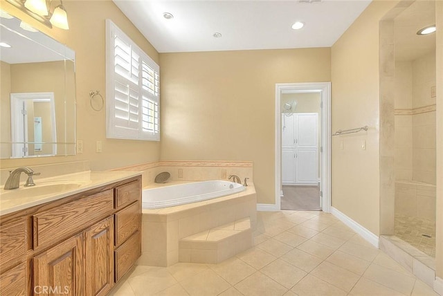 full bath featuring baseboards, a garden tub, a tile shower, tile patterned floors, and vanity