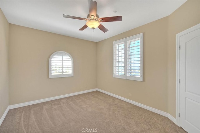 carpeted empty room featuring baseboards and ceiling fan