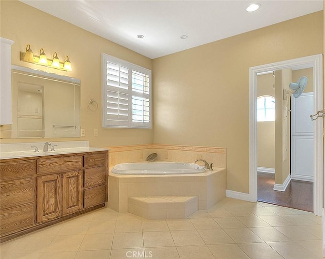 full bath with tile patterned flooring, a garden tub, vanity, and baseboards