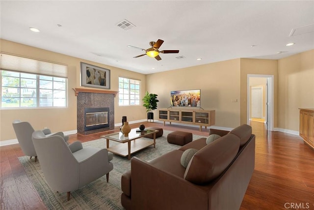 living room with a tiled fireplace, recessed lighting, wood finished floors, and visible vents