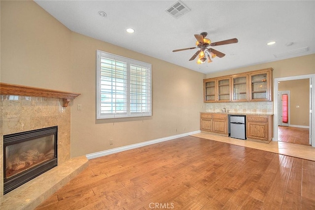 unfurnished living room with baseboards, light wood-style floors, visible vents, and a premium fireplace