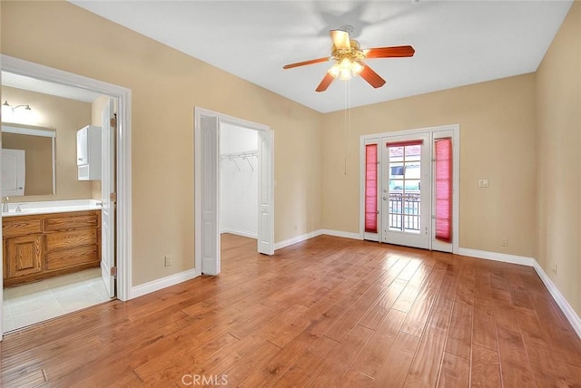 spare room with ceiling fan, baseboards, light wood-style flooring, and a sink