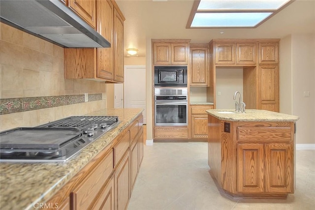 kitchen featuring a sink, tasteful backsplash, under cabinet range hood, and stainless steel appliances