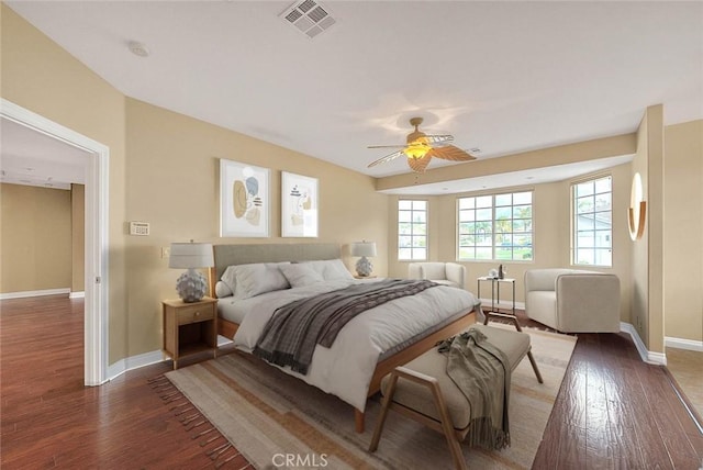 bedroom with wood finished floors, visible vents, and baseboards