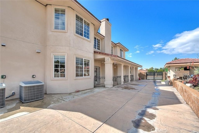 back of property featuring stucco siding, a gate, a patio, fence, and central AC unit