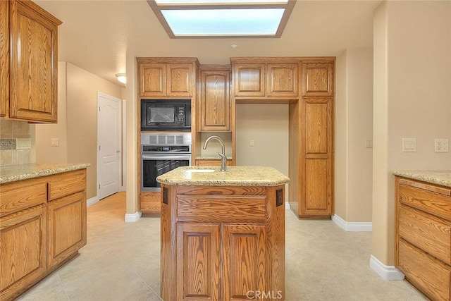 kitchen with light stone countertops, a sink, decorative backsplash, oven, and black microwave