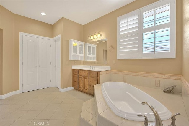 bathroom with tile patterned floors, baseboards, a garden tub, and vanity