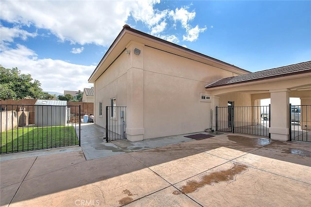 view of home's exterior with stucco siding, fence, a lawn, and a patio area