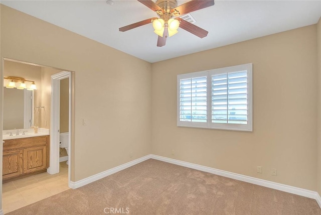 unfurnished bedroom with visible vents, baseboards, a sink, light colored carpet, and connected bathroom