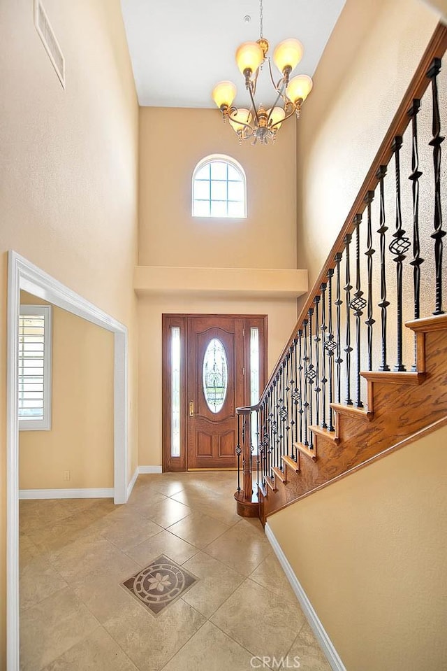 tiled entryway featuring visible vents, baseboards, an inviting chandelier, and stairs