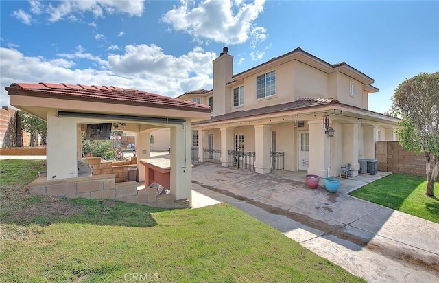 back of house with a patio, a lawn, fence, and stucco siding