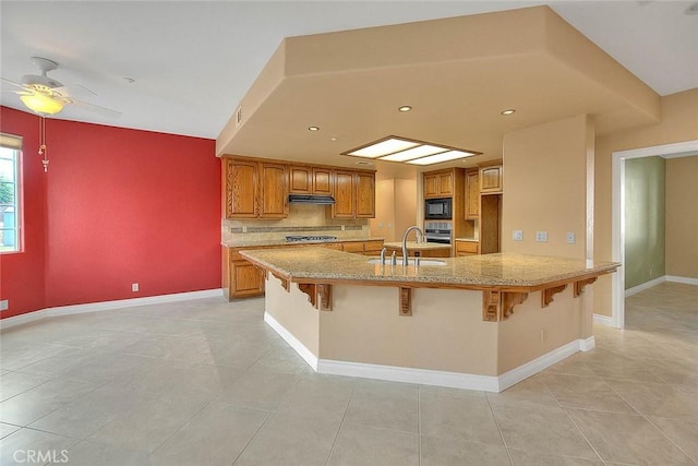 kitchen featuring a kitchen breakfast bar, tasteful backsplash, brown cabinets, and stainless steel appliances