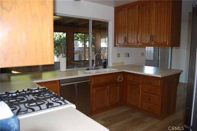 kitchen featuring brown cabinets, dishwasher, light countertops, and a sink