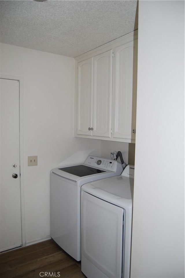 laundry area featuring washing machine and clothes dryer, cabinet space, a textured ceiling, and dark wood-style flooring