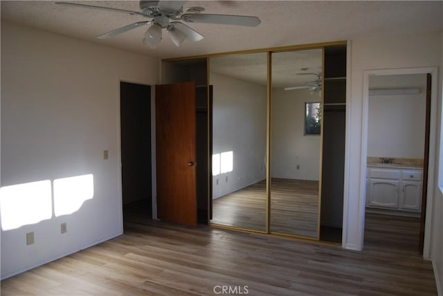 unfurnished bedroom featuring a textured ceiling, light wood-type flooring, a ceiling fan, and a sink