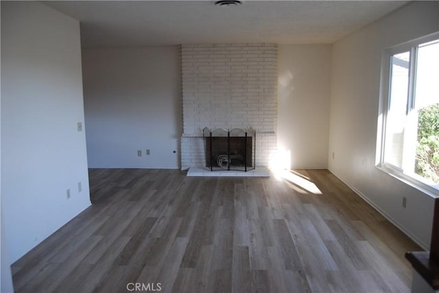 unfurnished living room featuring a fireplace, wood finished floors, and a healthy amount of sunlight