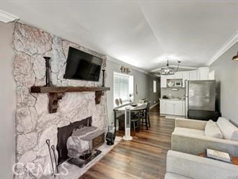 living area featuring vaulted ceiling, a fireplace, dark wood-style flooring, and ornamental molding