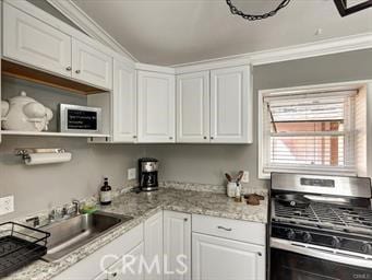 kitchen with ornamental molding, a sink, light stone counters, white cabinetry, and stainless steel gas range