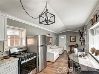 kitchen with a notable chandelier, stainless steel appliances, light wood-style floors, crown molding, and vaulted ceiling