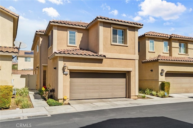 mediterranean / spanish-style home with stucco siding, a garage, driveway, and fence