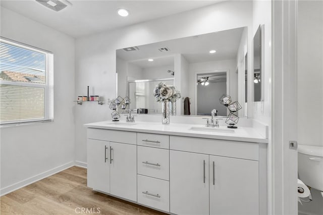 full bathroom with wood finished floors, visible vents, a stall shower, a sink, and toilet