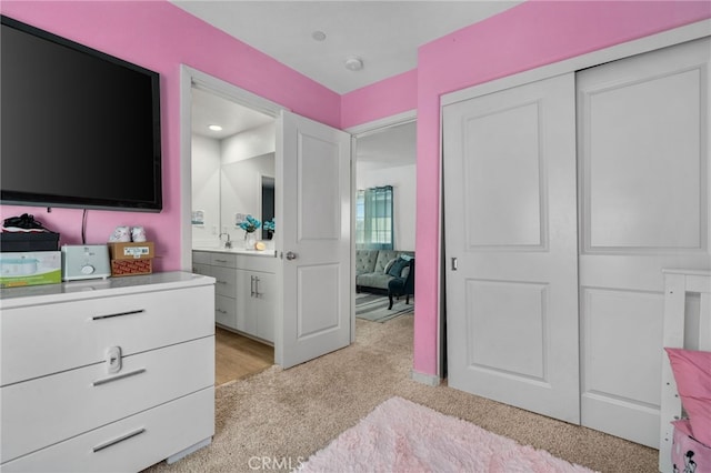 bedroom with light carpet, a closet, and connected bathroom