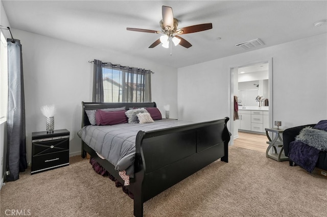 bedroom with a ceiling fan, light colored carpet, visible vents, and ensuite bathroom