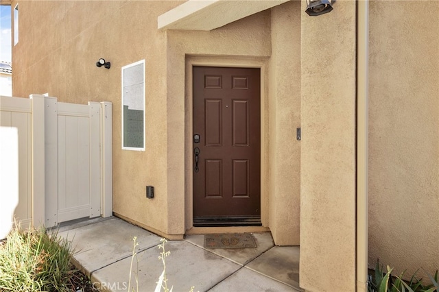 property entrance featuring fence and stucco siding