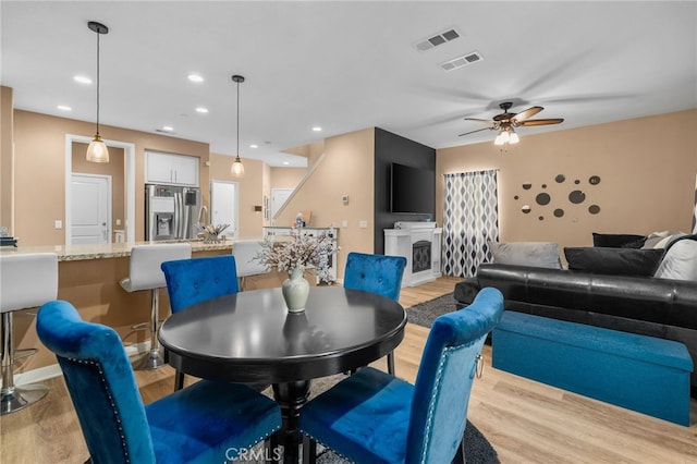 dining room featuring recessed lighting, visible vents, a fireplace, and light wood finished floors