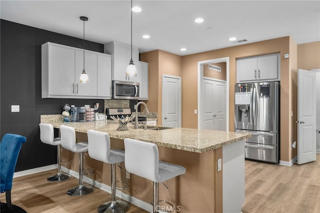 kitchen with visible vents, a breakfast bar, a sink, stainless steel appliances, and a peninsula