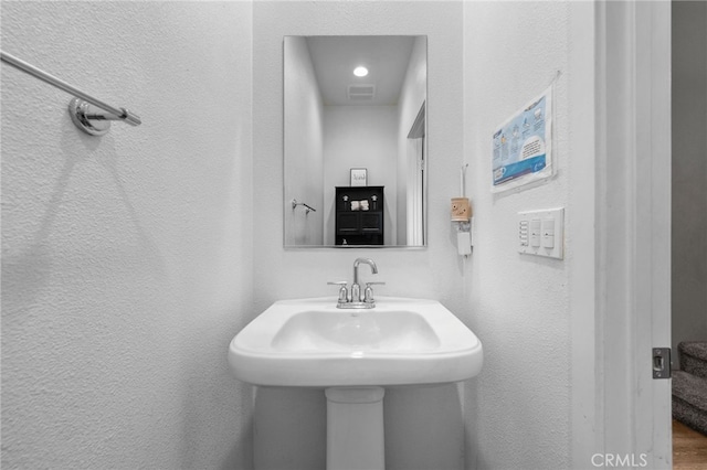 bathroom with a sink, visible vents, and a textured wall