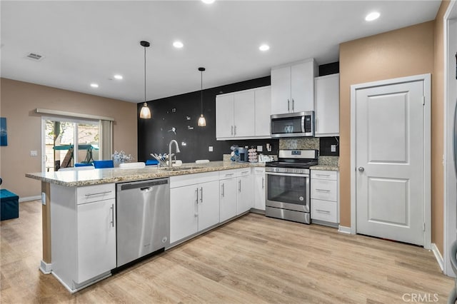 kitchen with white cabinetry, a peninsula, stainless steel appliances, and a sink