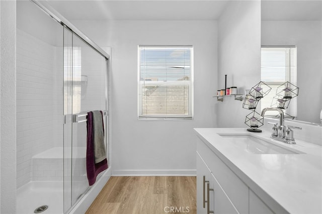 bathroom featuring vanity, a shower stall, wood finished floors, and baseboards