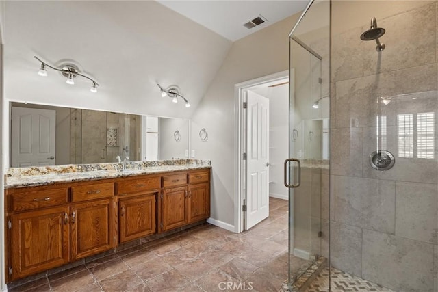 full bathroom featuring vanity, baseboards, visible vents, lofted ceiling, and a shower stall