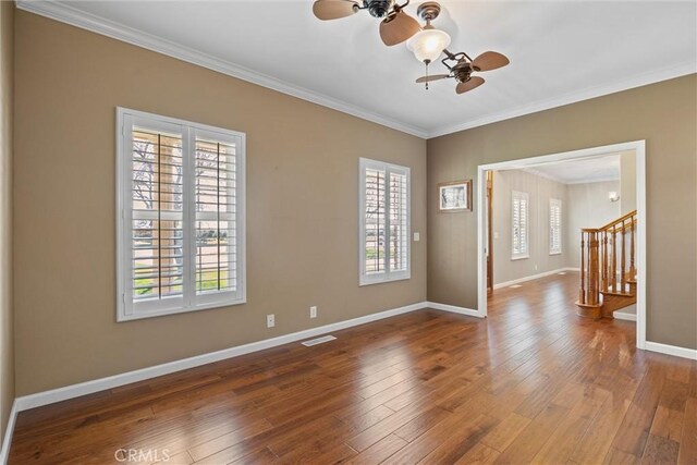 empty room featuring visible vents, ornamental molding, hardwood / wood-style flooring, baseboards, and stairs