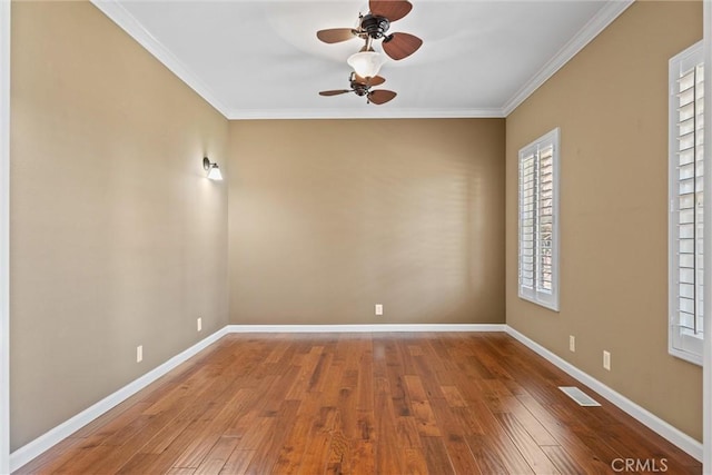 unfurnished room featuring visible vents, baseboards, ornamental molding, wood finished floors, and a ceiling fan