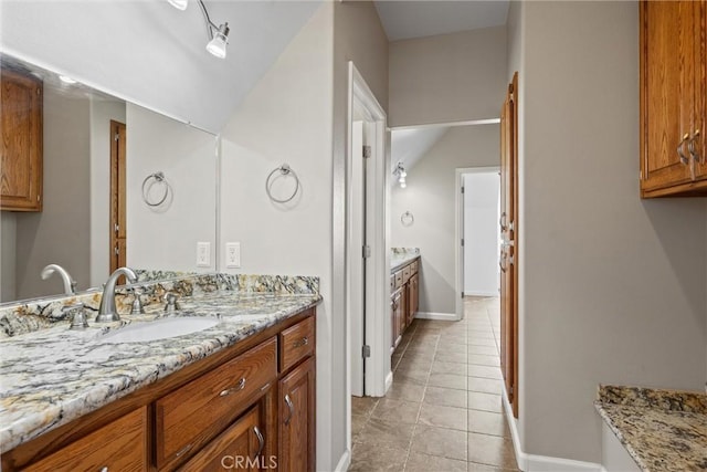 full bath with vanity, tile patterned floors, baseboards, and lofted ceiling