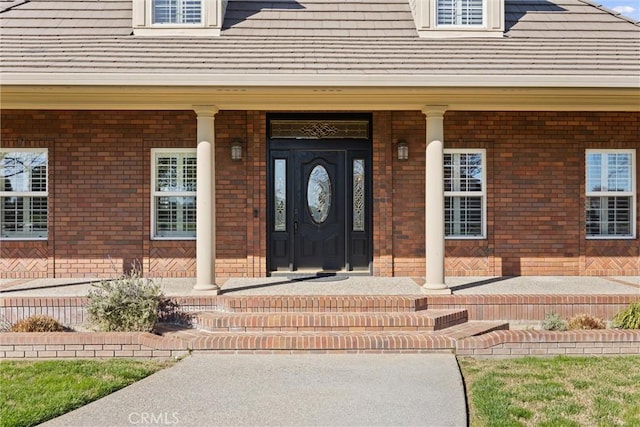 property entrance with brick siding and a porch