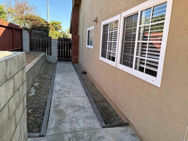 view of side of home with stucco siding and fence