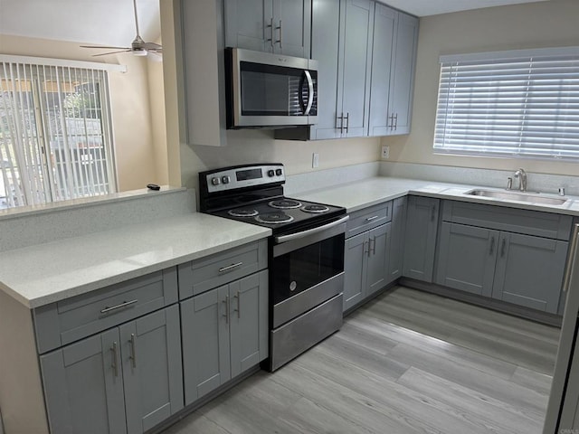 1549 Grand Teton Ct, Chula Vista, CA 91911 - kitchen with appliances with stainless steel finishes, gray cabinetry, a ceiling fan, light wood-type flooring, and a peninsula
