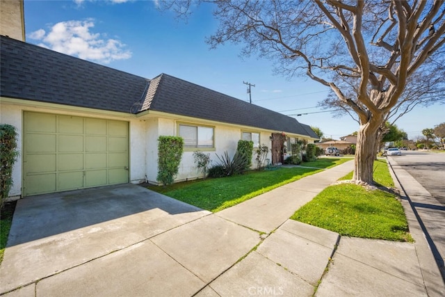 view of side of property with roof with shingles, mansard roof, an attached garage, stucco siding, and concrete driveway