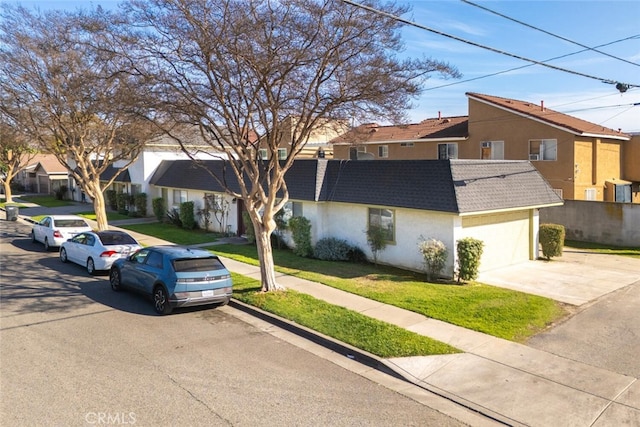 multi unit property with stucco siding, a front lawn, a residential view, an attached garage, and a shingled roof