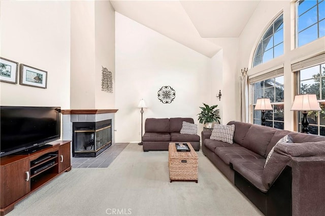 living area featuring a high ceiling, carpet flooring, and a tile fireplace