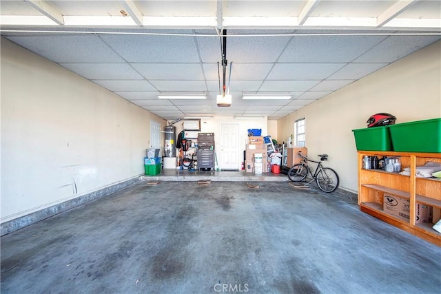 garage featuring baseboards, a garage door opener, and water heater